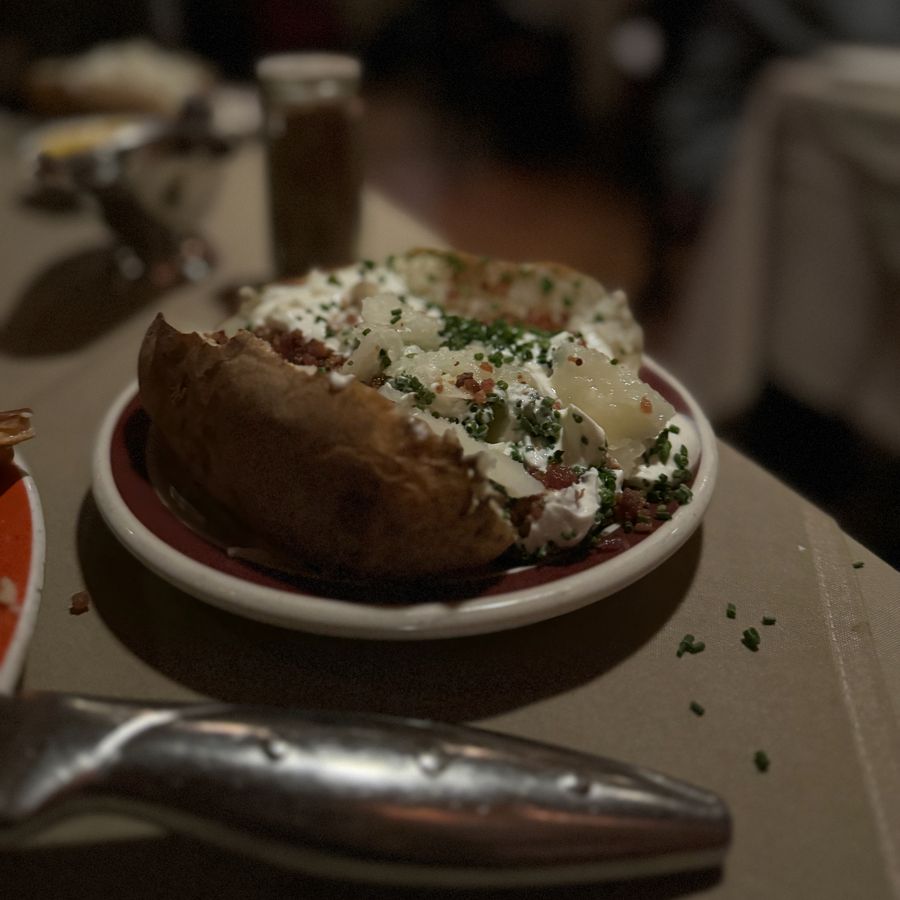 Loaded baked potato with sour cream, bacon and chives at House of Prime Rib, 2023