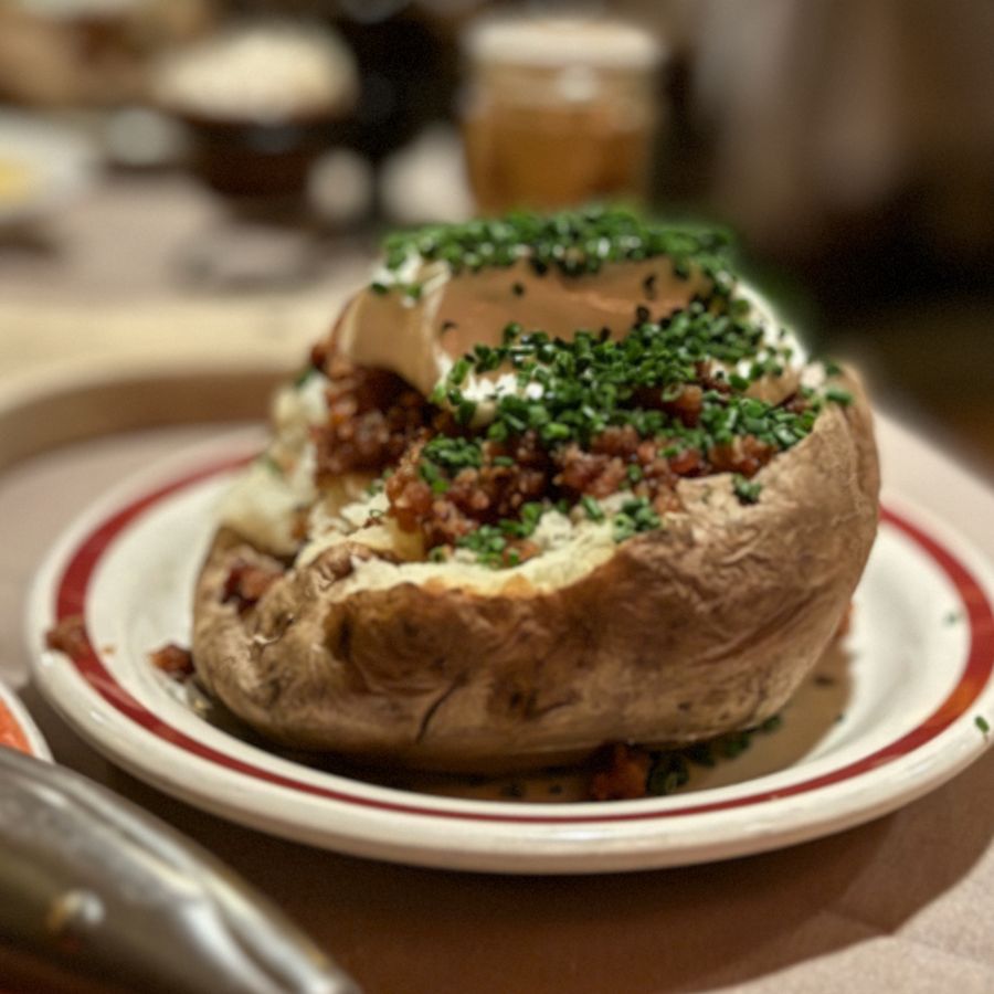 Loaded baked potato with sour cream, bacon and chives at House of Prime Rib, 2024